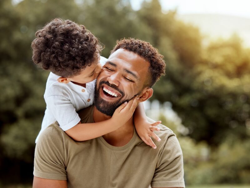Laughing father hugged from behind by his young son