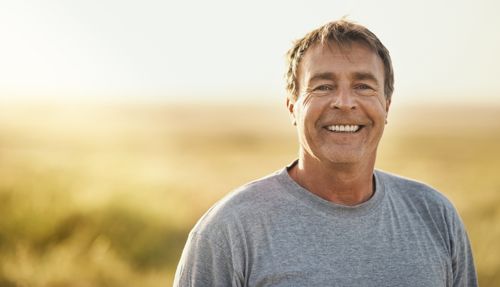 Smiling man standing outdoors in a sunlit field
